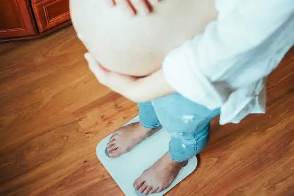 Image of woman weighing herself and experiencing weight gain through pregnancy Hickstead